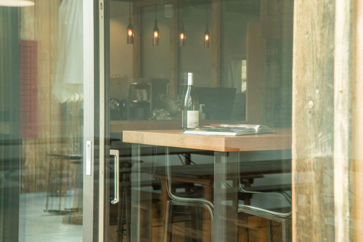 Bachmann Weingut - Blick durch das Fenster hinein mit Weinflasche und Ausstellungsbuch auf dem Tisch